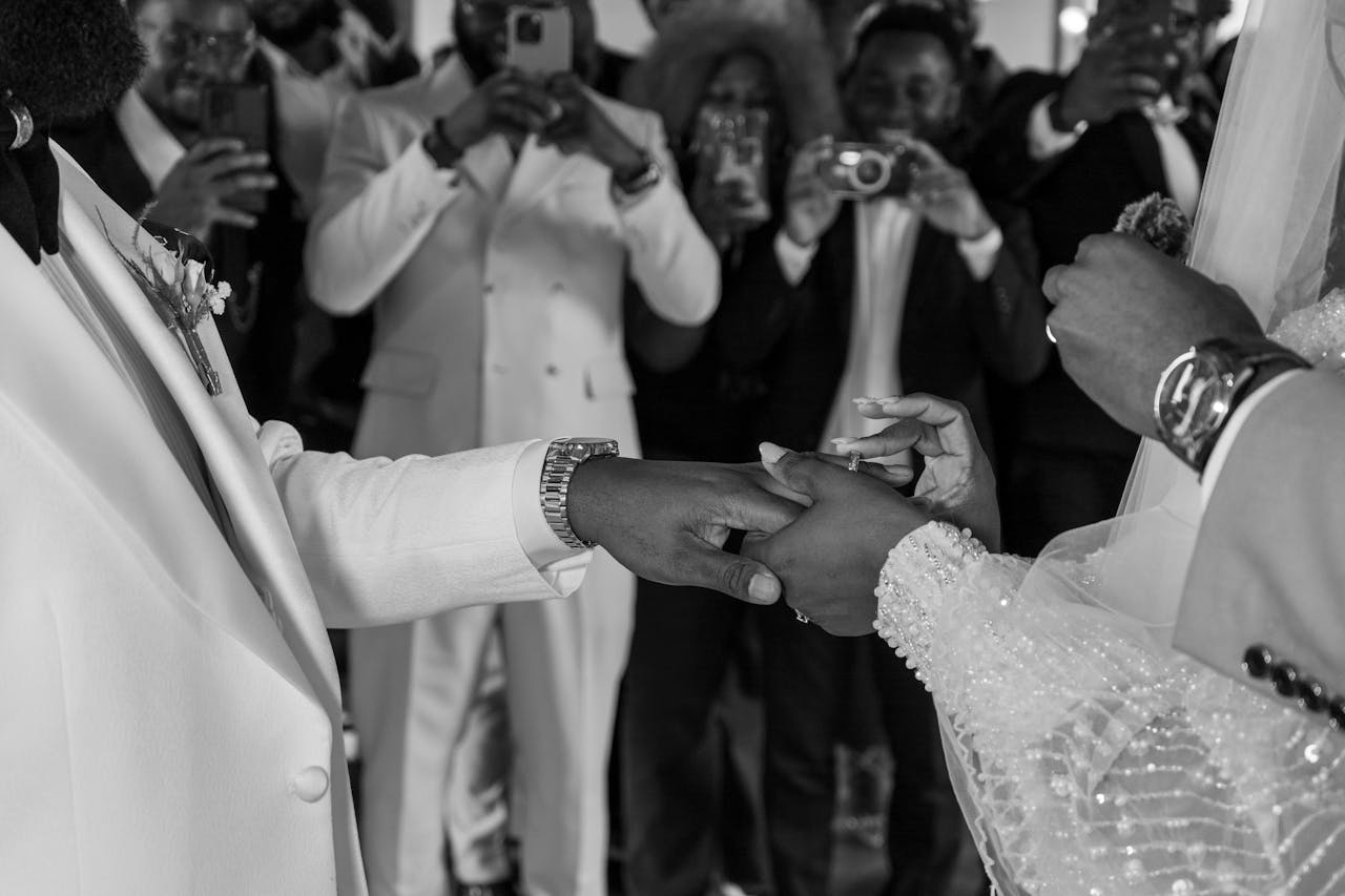 hero-img-02 A classic black and white photo capturing a couple exchanging rings during a wedding ceremony.